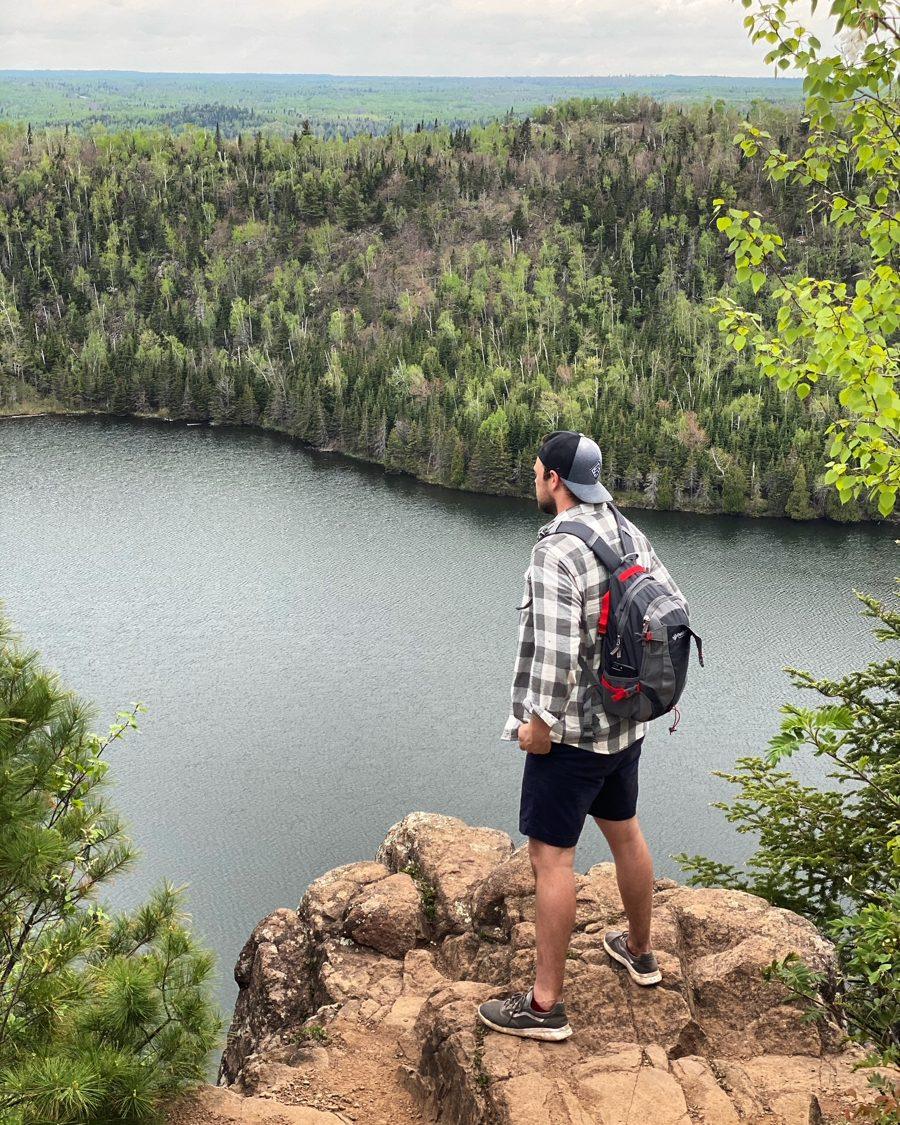 Andrew hiking on a rocky overlook above a lake